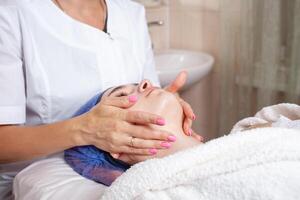 das Kosmetikerin Massagen das Gesicht im das Schönheit Salon foto