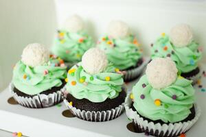 Gebäck Koch Fachmann bereit Cupcakes im bilden von Weihnachten Bäume. köstlich Süßigkeiten zum irgendein Urlaub, Geschenk. Grün ausgepeitscht Creme. foto