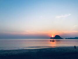 Orange Horizont reflektieren auf Ruhe Ozean Wellen beim Sonnenuntergang durch das Strand foto