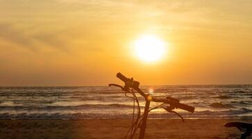 Silhouette von ein Fahrrad im das Hintergrund von das steigend Sonne auf das Strand im das Morgen. foto