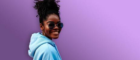 ai generiert Studio Schuss von jung dunkel gehäutet Frau tragen Sonnenbrille und lächelnd während isoliert Über lila Hintergrund. Header mit leeren Raum zum Text, Logo oder Produkt. foto