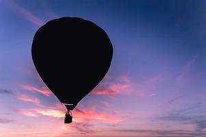 dunkle Silhouette des Heißluftballons oder des Aerostats auf dem Hintergrund des bunten Sonnenuntergangs foto