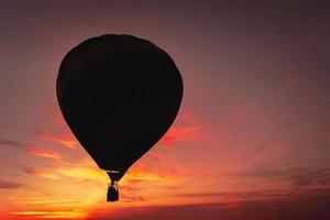 dunkle Silhouette des Heißluftballons oder des Aerostats auf dem Hintergrund des bunten Sonnenuntergangs foto