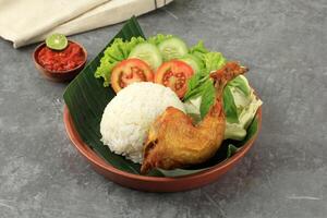 indonesisch Stil gebraten Hähnchen serviert mit gedämpft Reis und würzig Einfügen foto