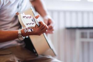 ein jung Mann ist üben spielen Gitarre im ein Musik- trainieren Zimmer Vor durchführen im bestellen zu reduzieren das Fehler von spielen Gitarre auf Bühne. schließen oben jung Mann ist halten Gitarre Akkorde zum ausüben. foto