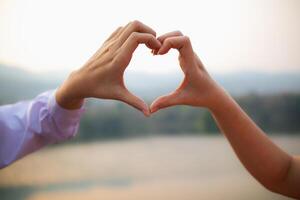 Frau angehoben ihr Hände und gemacht Herz Symbol zu ausdrücken Bedeutung von Liebe Freundschaft und Freundlichkeit zu ihr freunde und Liebhaber. Frau Verwendet ihr Hände zu machen ein Herz Symbol Das meint Liebe und Freundschaft. foto