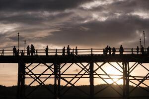 Silhouette Touristen Reise Gehen auf hölzern mon Brücke foto