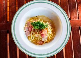 Spaghetti Carbonara mit Speck, Schinken und Gemüse im Schüssel foto