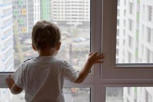 schönes Baby mit Kindergesicht posiert Fotograf in der Nähe von Fenster foto