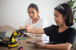 erfinderisch Kinder lernen beim Zuhause durch Codierung Roboter Autos und elektronisch Tafel Kabel im Stengel. konstruieren Roboter Autos beim Zuhause foto