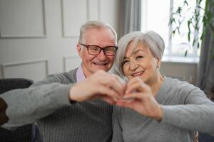 Liebe Herz gestalten Frieden. Senior älter Paar Herstellung Herz gestalten mit ihr Hände. Erwachsene reifen alt Mann Ehefrau zeigen Herz unterzeichnen. glücklich Rentner Familie. ich Liebe Sie glücklich Valentinsgrüße Tag foto