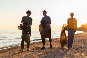 Erde Tag. Freiwillige Aktivisten Mannschaft sammelt Müll Reinigung von Strand Küsten Zone. Frau mans mit Müll im Müll Tasche auf Ozean Ufer. Umwelt Erhaltung Küsten Zone Reinigung foto