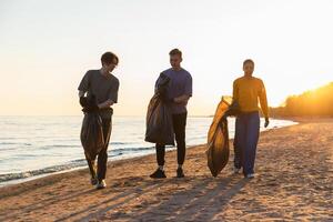 Erde Tag. Freiwillige Aktivisten Mannschaft sammelt Müll Reinigung von Strand Küsten Zone. Frau mans mit Müll im Müll Tasche auf Ozean Ufer. Umwelt Erhaltung Küsten Zone Reinigung foto