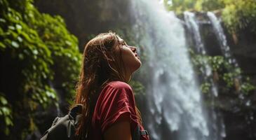 ai generiert ein jung Frau im Vorderseite von ein Wasserfall suchen zu das Himmel foto