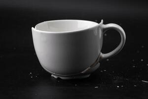 groß Weiß Becher mit Risse. Weiß Tasse zum Tee oder Suppe mit Risse isoliert auf dunkel Hintergrund. gebrochen Keramik Tasse schließen hoch. Symbol von Scheidung oder Verlust foto