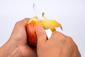 Hand Peeling Apfel mit Messer schließen hoch. Frau Peeling ein rot Apfel im das Küche. foto