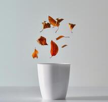 ai generiert ein Weiß Tasse mit Blätter fallen von es foto