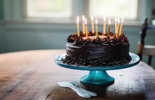 ai generiert ein Schokolade Geburtstag Kuchen mit zündete Kerzen auf es Sitzung auf ein Blau Stand foto