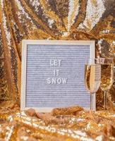 Filzbriefbrett auf goldenem glänzendem Hintergrund mit Sektgläsern schneien lassen foto