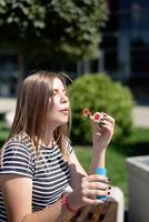 glückliche schöne kaukasische Frau, die an einem sonnigen Tag Seifenblasen im Freien bläst foto