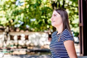 Nahaufnahme Porträt einer schönen jungen kaukasischen Frau, die an einem sonnigen Tag im Freien lächelt und nach oben schaut foto