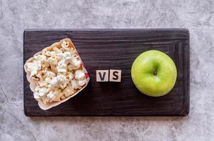 Popcorn versus Apfel Draufsicht auf dunklem Hintergrund