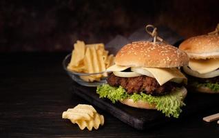 eine Reihe hausgemachter köstlicher Burger aus Rindfleisch, Zwiebeln, Käse und Salat auf dunklem Holzhintergrund foto