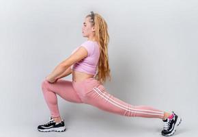 Akrobatin trägt rosa Sportkleidung, die sich im Studio auf grauem Hintergrund ausdehnt