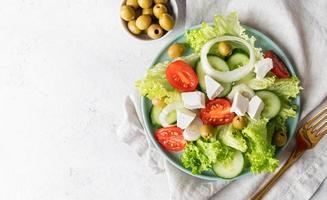 Griechischer Salat mit Feta-Käse, frischem Gemüse und Oliven auf weißem rustikalem Hintergrund Draufsicht mit Kopienraum