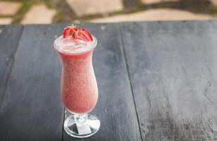 Erdbeere Smoothie auf hölzern Tisch. Erdbeere Milchshake auf hölzern Tabelle mit verschwommen Hintergrund. schließen oben von gesund Erdbeere Smoothie auf Holz mit verschwommen Hintergrund foto