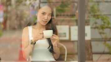 asiatische Teenager-Mädchen hält eine Kaffeetasse in einem Café.