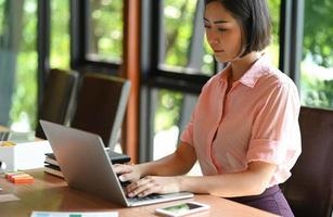 asiatische Teenager-Frau verwendet einen Laptop im Büro.