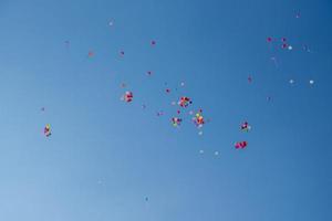 Ballons in verschiedenen Farben, die in den blauen Himmel fliegen foto