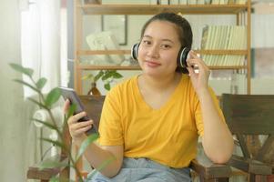 junges Mädchen im gelben Hemd hört zu Hause Musik über eine App auf dem Smartphone. foto