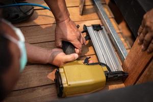 Hand-Mann-Zimmermann mit Luftnagelpistole, um Holztisch im Garten zu vervollständigen foto