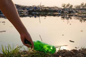Handaufheben grüne Glasflasche und Flasche am großen Müllhintergrund des Berges