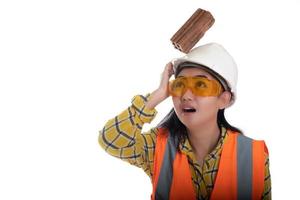 Der Stockblockstein fiel auf den Kopf der jungen Frau des asiatischen Ingenieurs auf den Helmarbeiter auf weißem Hintergrund, das erste Konzept der Bereichsbausicherheit