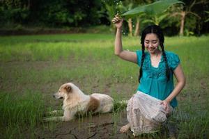 Porträt einer jungen asiatischen Frau mit schwarzen Haaren, die ein Bananenblatt im Regen am grünen Gartenhintergrund halten foto