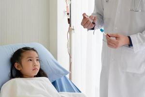 In der pädiatrischen Krankenhausabteilung entnimmt der asiatische Arzt einem jungen Mädchen Blut, um es zum Test zu schicken. Gesundheits- und Medizinkonzept