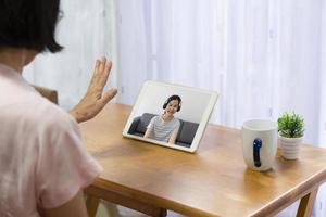 Ältere asiatische Frau, die Computer verwendet, um Videoanrufe zu machen und mit Tochter von zu Hause aus zu sprechen foto