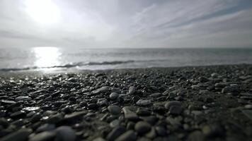 schön verlassen Strand. Aktion.hell Wellen von das Meer Prügel auf klein Steine und Sie können sehen das hell Sonne leuchtenden direkt in das Kamera. foto