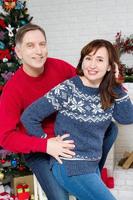 Ehepaar mittleren Alters im Zimmer mit Weihnachtsbaum und geschmücktem Kamin, liebevolle Familie foto