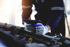 Auto Mechaniker ist reparieren ein Auto im das Garage. prüfen das Sicherheit von das Auto Motor im das Garage Reparatur Bedienung Konzept. foto