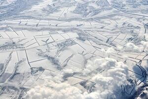 luftwolkengebilde blick über die wolkenspitze zu schneebedeckten flüssen, straßen, städten und feldern, winterluft foto