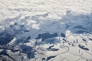 luftaufnahme über wolkenoberseite zu schneebedeckten flüssen, feldern und straßen, winterfrische frostige luft foto