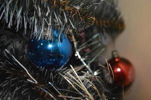 Weihnachtsbaum mit Spielzeug und leuchtenden Girlanden zu Hause und im Bürohintergrund foto