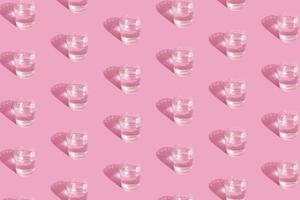Gläser mit Wasser- und Schattenmuster auf rosa Hintergrund foto