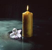 ein Kerze und Blume auf ein schwarz Oberfläche foto