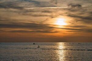 Sonnenuntergang, beleuchtet Meer. sandig Strand im das Vordergrund. Licht Wellen. baltisch Meer foto