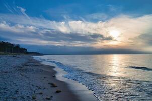 Sonnenuntergang auf das Westen Strand auf das baltisch Meer. Wellen, Strand, wolkig Himmel. Landschaft foto